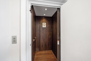 An elevator with a wooden interior, a small framed picture on the wall, and a handrail on the right side. - Warm & Modern 3Bdrm NoLibs Condo - Sleeps 7! (Philadelphia)