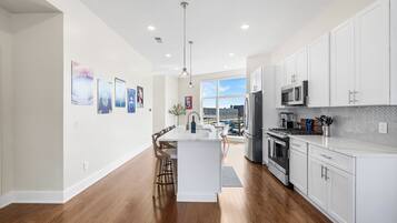 A modern kitchen with white cabinetry, a central island, and a dining area with chairs.