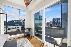 A modern room with large windows, a balcony, and a view of the cityscape. - Warm & Modern 3Bdrm NoLibs Condo - Sleeps 7! (Philadelphia)