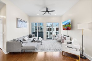 A modern living room with a grey sectional sofa, a white armchair, a round coffee table, and a floor lamp. - Warm & Modern 3Bdrm NoLibs Condo - Sleeps 7! (Philadelphia)