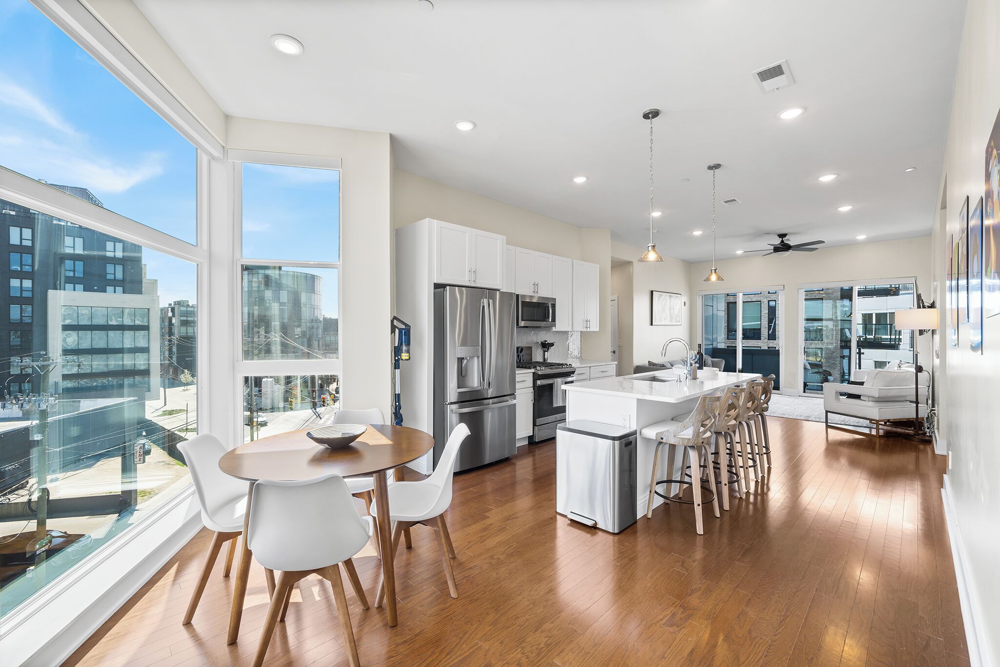 A modern kitchen with white cabinetry, stainless steel appliances, and a large island with bar stools.