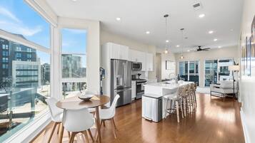 A modern kitchen with white cabinetry, stainless steel appliances, and a large island with bar stools.