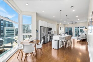 Una cocina moderna con armarios blancos, electrodomésticos de acero inoxidable y una isla grande con taburetes de bar.
