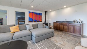 Una sala moderna con un sofá modular, una mesita de centro y una zona de cocina con armarios de madera y encimera.