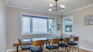 Comedor con mesa de vidrio, seis sillas y una lámpara moderna.