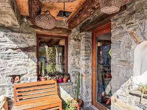 A stone building with a wooden bench and potted plants. - Casa Serena by Interhome (Mergoscia)