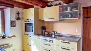 Eine Küche mit Backofen, Mikrowelle und Spüle. Eine Fenster befindet sich links.