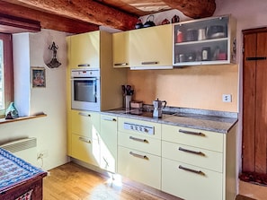 A kitchen with a built-in oven, a microwave, and a sink. There is a window on the left side. - Casa Serena by Interhome (Mergoscia)