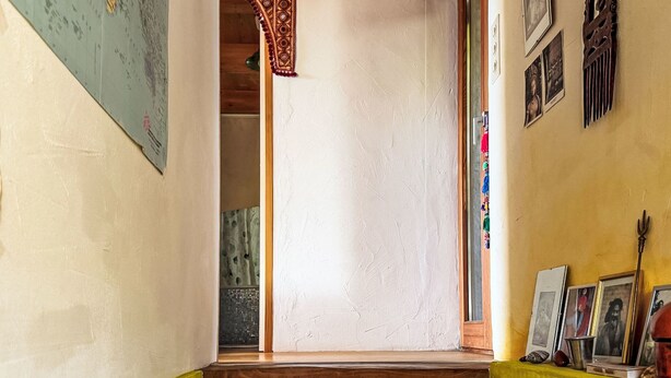 Ein Flur mit einer Holztür, einer Karte an der Wand und gerahmten Bildern auf der rechten Seite.