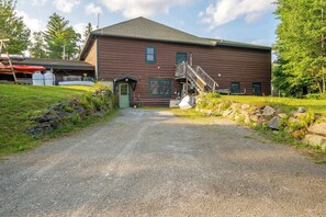 A wooden building with a gravel driveway leading to a green door.