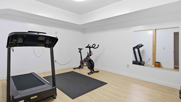 A gym with a treadmill, stationary bike, and elliptical machine.
