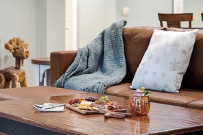 A wooden coffee table with a fruit platter, cheese, crackers, and a copper mug with a mint garnish. - Rangeley Lakefront 3BR | Private Dock, Dogs OK (Rangeley)