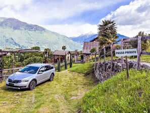 Ein Privatgrundstück mit geparktem Auto, Steinmauern und einem Schild mit der Aufschrift 'PASSO PRIVATO'.