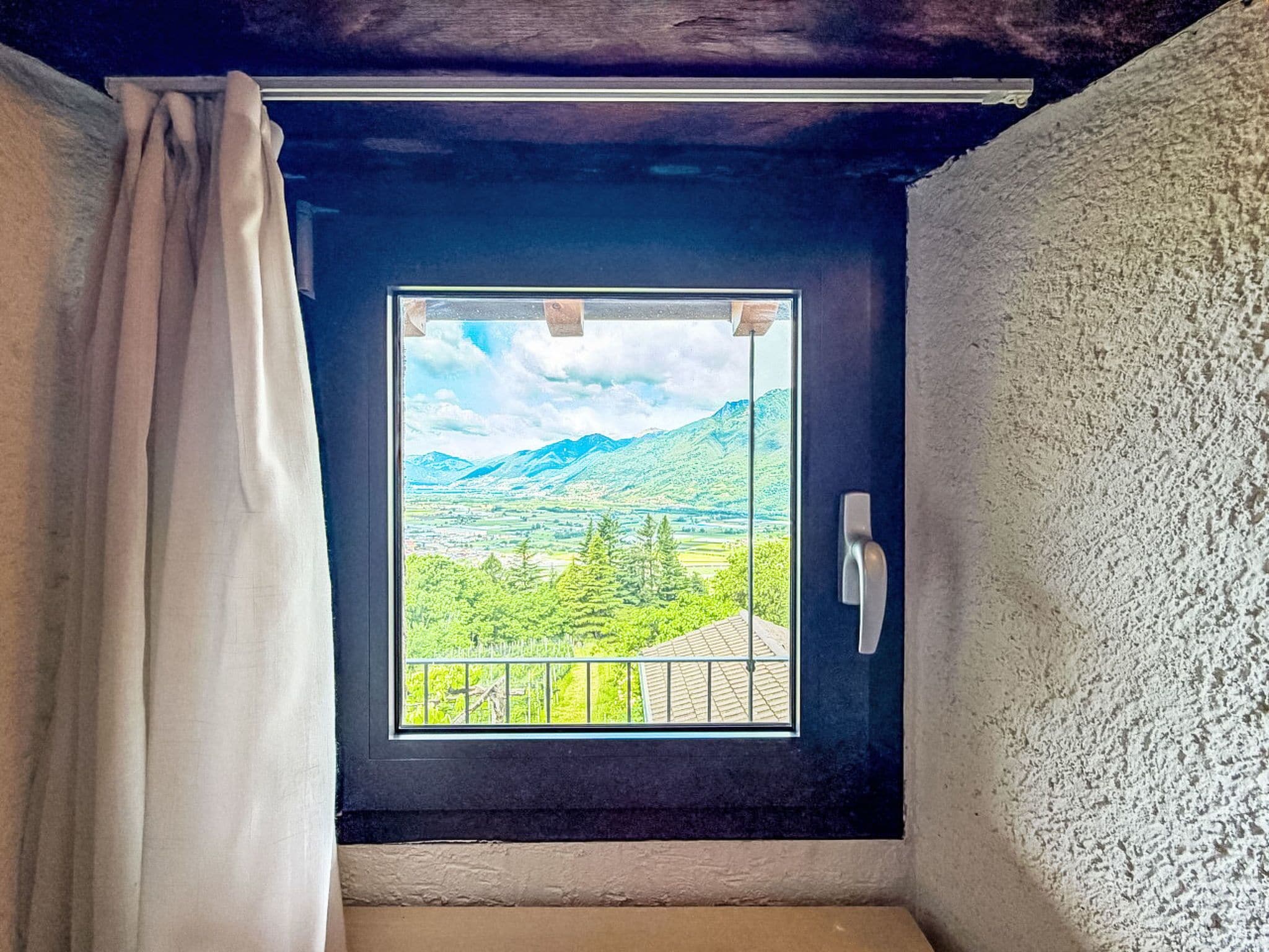 A room with a window overlooking a mountainous landscape.