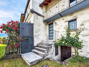 Ein Gebäude mit einer Steintreppe, die zu einer Holztür, einem Metallgitter und einem Balkon mit Metallgeländer führt.