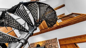 A spiral staircase with a metal railing and wooden beams.