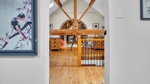 A room with wooden beams, a brick fireplace, and a wooden floor.