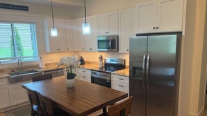 Una cocina moderna con armarios blancos, electrodomésticos de acero inoxidable y una mesa de comedor de madera con sillas.