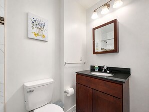 Ein Badezimmer mit Toilette, Waschbecken, Waschtisch, Spiegel und einer Wandleuchte.