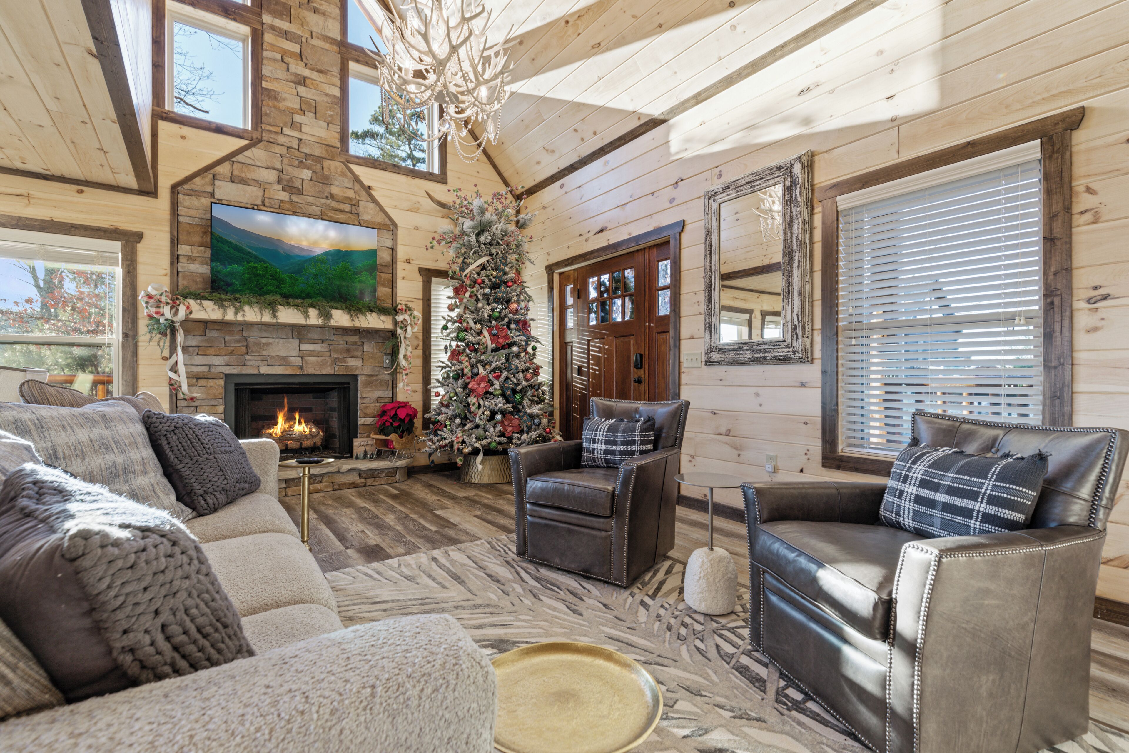 A cozy living room with a fireplace, leather sofas, a Christmas tree, and a large painting on the wall.