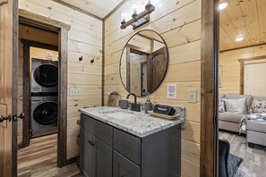 Ein kleines Badezimmer mit Waschbecken, Spiegel und zwei Wandwaschmaschinen.