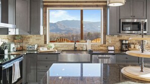A modern kitchen with a large window, stainless steel appliances, and a granite countertop. - The Overlook at Settlers Ridge (Sevierville)