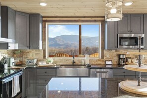 Eine moderne Küche mit großem Fenster, Edelstahlgeräten und einer Arbeitsplatte aus Granit.