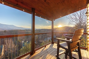 Eine Holzterrasse mit Blick auf Berge und einen Sonnenuntergang.