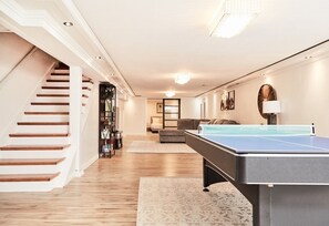 Ein geräumiges Wohnzimmer mit einer Tischtennisplatte, einer Treppe und einer gemütlichen Sitzecke.