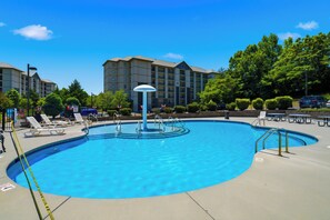 A swimming pool with lounge chairs and a building in the background. - Sleeps 6, Condo with Resort Indoor Pool, Fireplace, 5 Mi to Dollywood (Pigeon Forge)