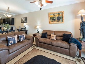 A living room with two brown sofas, a dining table, and a painting on the wall. - Sleeps 6, Condo with Resort Indoor Pool, Fireplace, 5 Mi to Dollywood (Pigeon Forge)