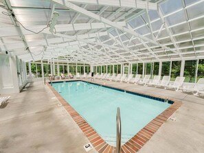 Ein Hallenbad mit Glasdach, umgeben von Liegestühlen.
