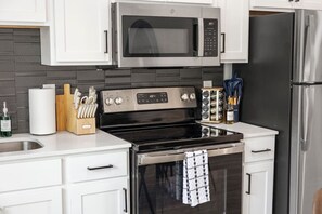 Eine moderne Küche mit Edelstahlgeräten, einer Mikrowelle, einem Backofen und einem Kühlschrank.
