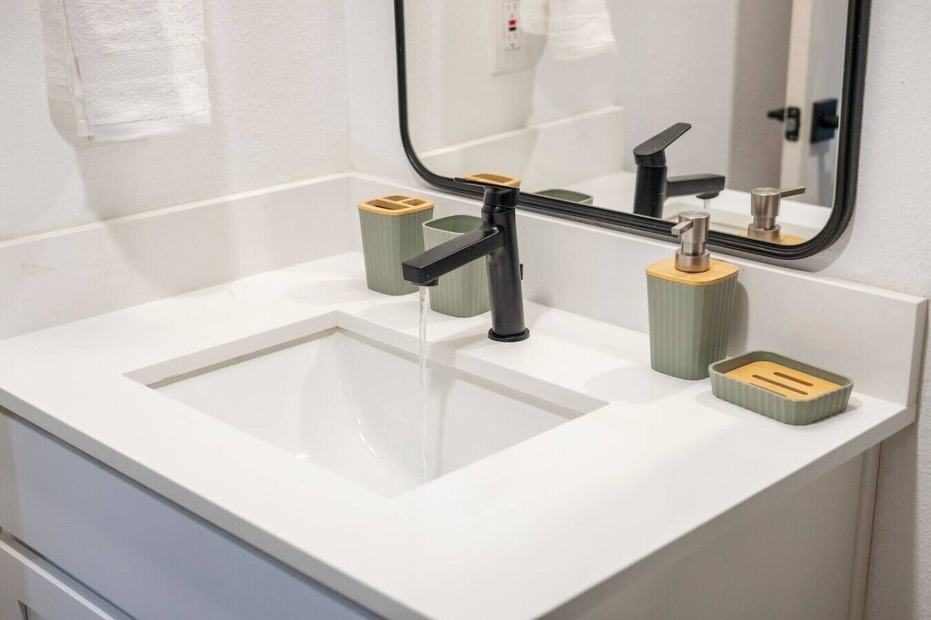 A bathroom with a white sink, a mirror, and two soap dispensers.
