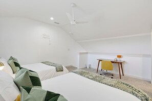 Een slaapkamer met twee bedden, een bureau, een stoel en een plafondventilator.