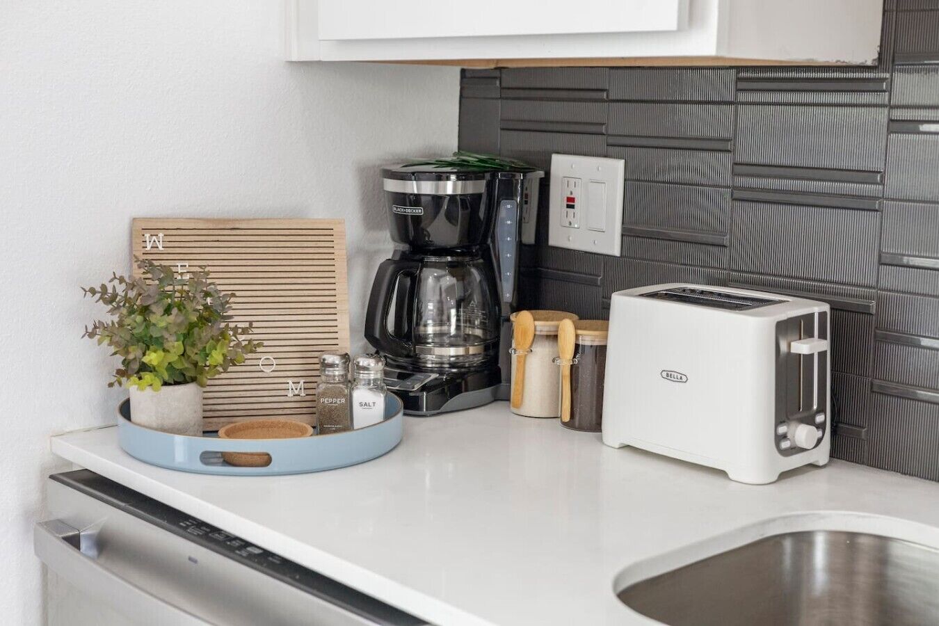 A kitchen with a coffee maker, toaster, and a plant on the counter.