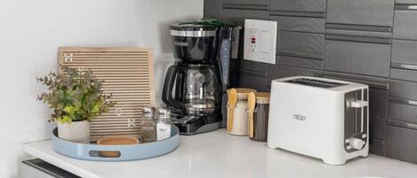 Une cuisine équipée d’une machine à café, d’un grille-pain et d’une plante posée sur le plan de travail.