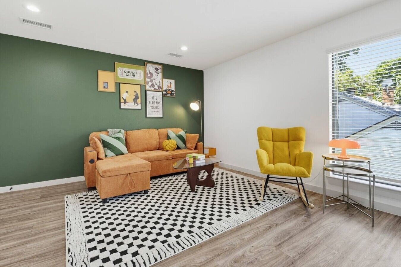 A living room with a sofa, armchair, and a patterned rug.