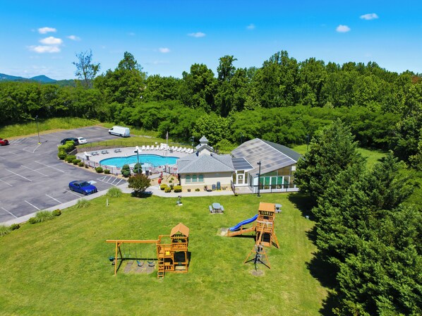 A building with a swimming pool, a playground, and a parking lot.