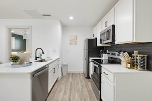 A modern kitchen with white cabinetry, a black refrigerator, a microwave, and a coffee maker. - Sleeps 3 ~ Near American Airlines Center + the Medical District + Downtown/Uptown (Dallas)