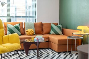 Ein modernes Wohnzimmer mit Sofa, Sessel, Couchtisch und Lampe.