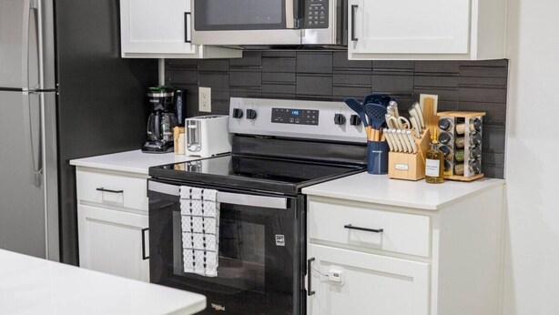 Una cocina moderna con un refrigerador de acero inoxidable, un microondas, una estufa y un horno empotrado.