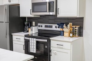 Una cocina moderna con un refrigerador de acero inoxidable, un microondas, una estufa y un horno empotrado.