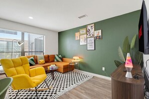 Een moderne woonkamer met een bank, fauteuil en een lavalampe.