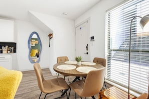 A modern dining area with a round table, four chairs, and a mirror on the wall. - Sleeps 3 ~ Near American Airlines Center + the Medical District + Downtown/Uptown (Dallas)