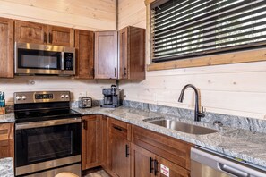 A kitchen with wooden cabinets, a stainless steel microwave, a stove, a coffee maker, and a dishwasher. - Sleeps 16, Private Heated Indoor Pool, Theater, 1 Mi to Downtown Gatlinburg (Gatlinburg)