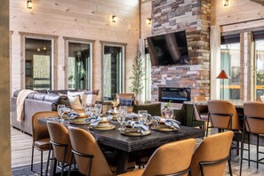 A dining area with a large table set for six, surrounded by chairs, and a stone fireplace. - Mountain Explorers Retreat (Gatlinburg)