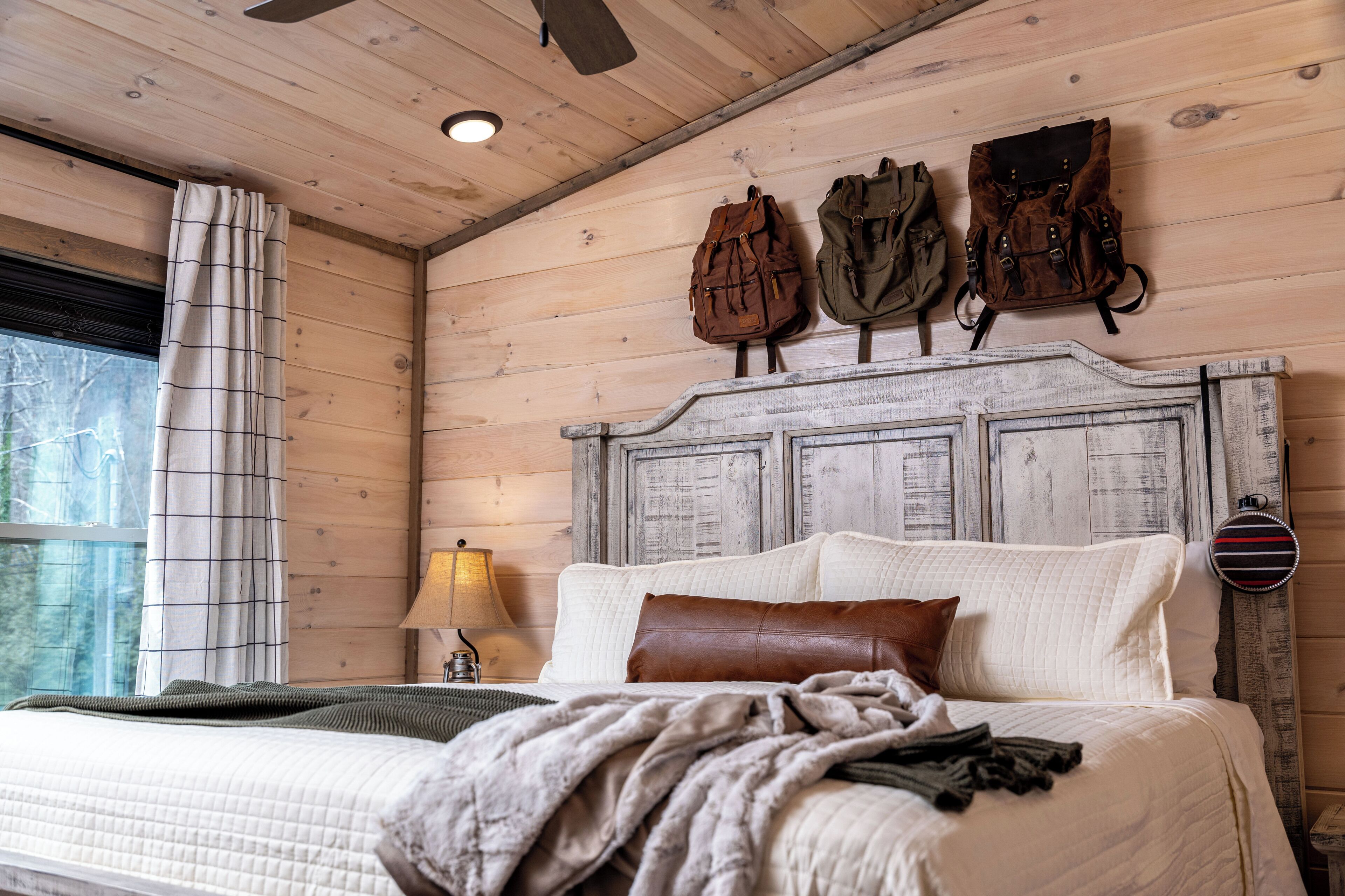 A bed with a headboard, a lamp, and a window with curtains.