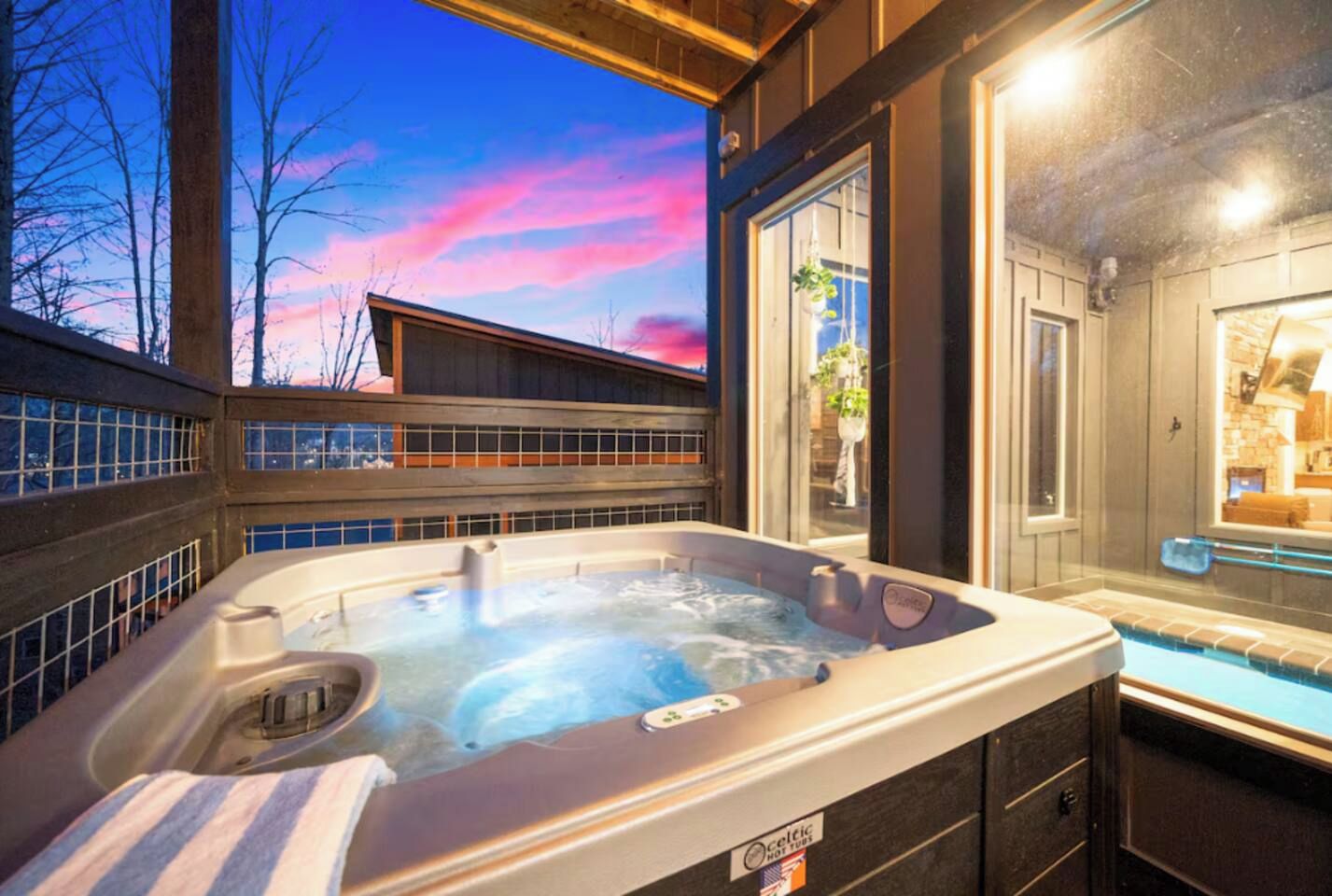 Ein Whirlpool mit Blick auf ein Gebäude und Bäume, umgeben von einer Holzterrasse.