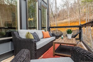 A wicker sofa with cushions, a small table, and chairs on a balcony with a view of trees and a fence. - Sleeps 16, Private Heated Indoor Pool, Theater, 1 Mi to Downtown Gatlinburg (Gatlinburg)